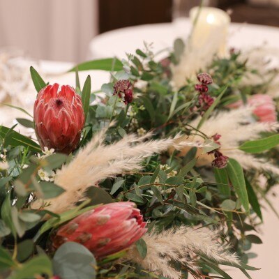 くすみグリーンをベースに赤い花をポイントに取り入れたメインテーブル装花。
ワイルドフラワーやパンパスグラスを使い、
フローリストさんがオシャレにアレンジしてくれました。