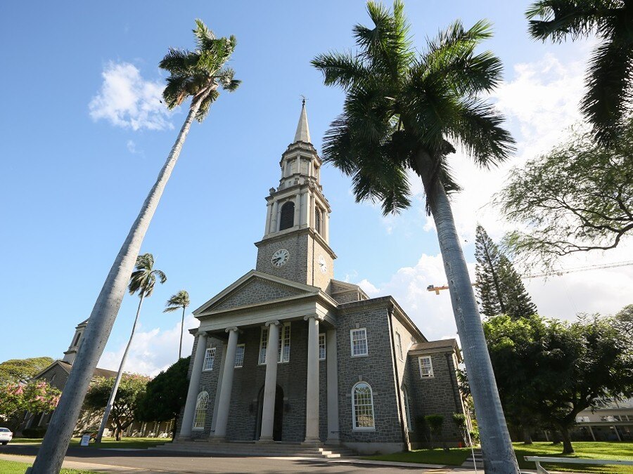 高くそびえるヤシの木と、空にむかって尖塔が印象的な教会。広いお庭の記念撮影も人気