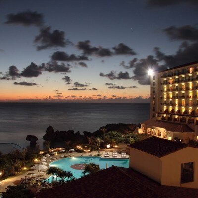 空がオレンジ色に染まる夕暮れ時は、プールがライトアップされて幻想的な美しさ<br>【外観】南欧風ホテルの外観
